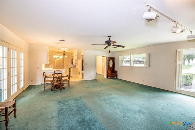 carpeted living area with ceiling fan with notable chandelier and a wealth of natural light