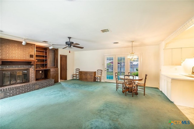 dining space with carpet floors, a ceiling fan, a brick fireplace, and visible vents