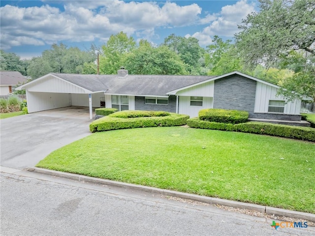 ranch-style home featuring a front yard, roof with shingles, a chimney, driveway, and a carport