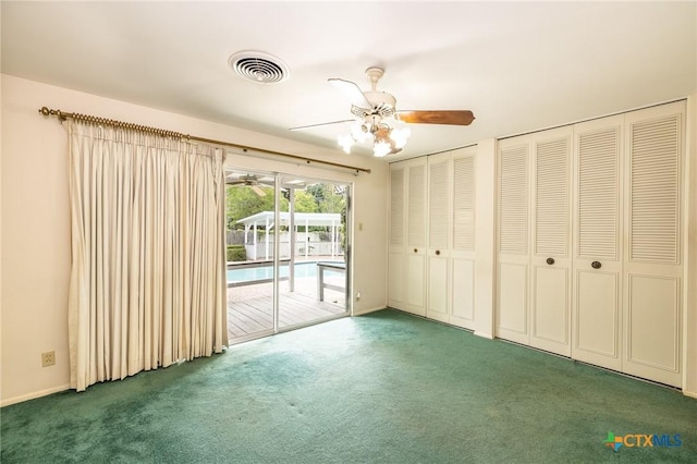 unfurnished bedroom with ceiling fan, visible vents, two closets, access to outside, and carpet