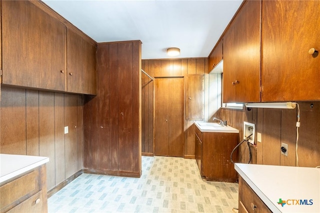 laundry room featuring cabinet space, wooden walls, a sink, hookup for a washing machine, and electric dryer hookup