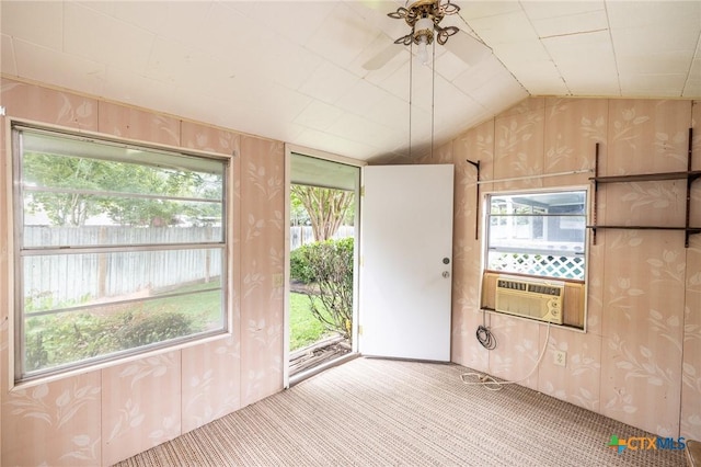 carpeted empty room featuring a ceiling fan, vaulted ceiling, and cooling unit