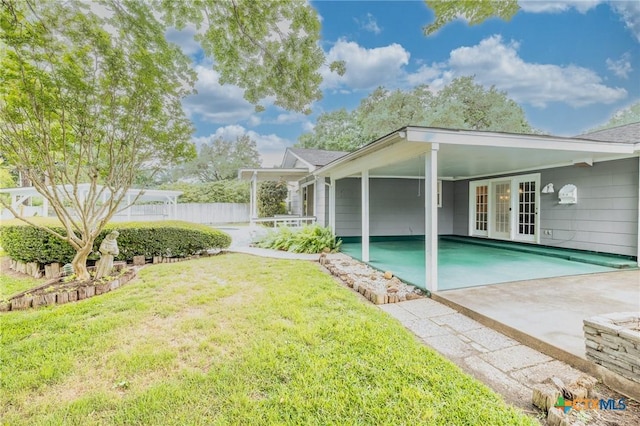 exterior space featuring fence, french doors, a carport, a yard, and driveway