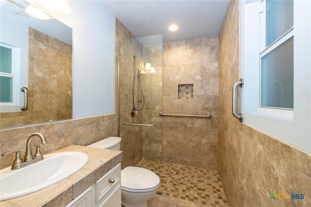 full bath with toilet, tile walls, a tile shower, and vanity