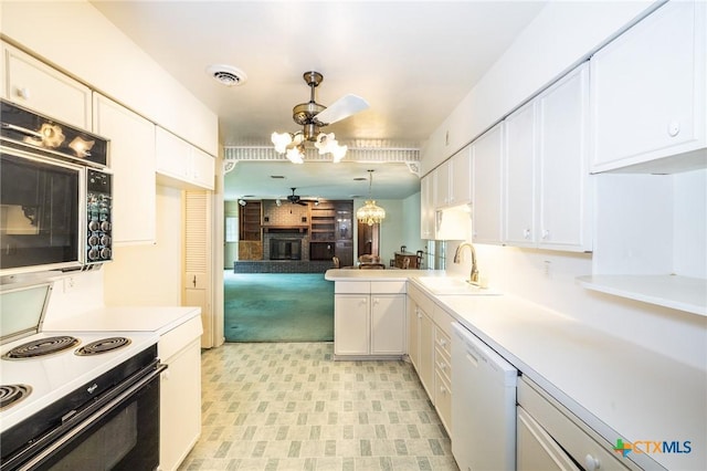 kitchen with a fireplace, white dishwasher, a sink, ceiling fan with notable chandelier, and range with electric cooktop