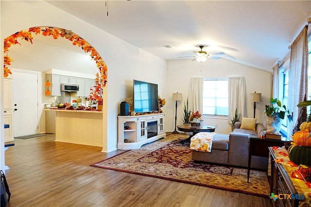 living room with vaulted ceiling, ceiling fan, and light wood-type flooring