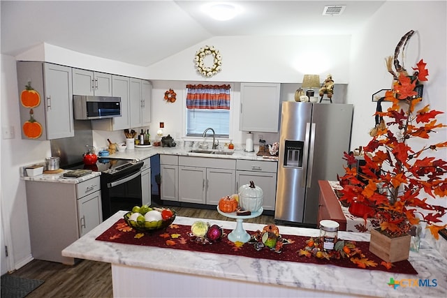 kitchen featuring stainless steel appliances, gray cabinetry, dark hardwood / wood-style floors, vaulted ceiling, and sink