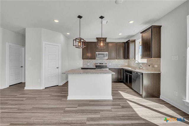 kitchen with stainless steel appliances, tasteful backsplash, a kitchen island, and pendant lighting