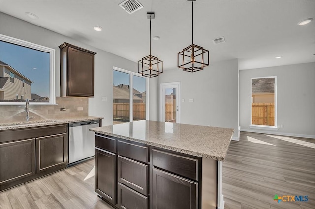 kitchen with sink, dark brown cabinets, a kitchen island, decorative light fixtures, and stainless steel dishwasher