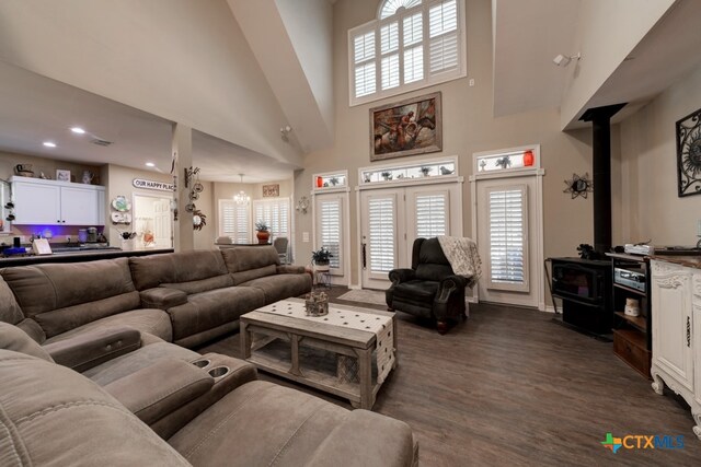 living room with a wood stove, dark hardwood / wood-style flooring, a high ceiling, and an inviting chandelier