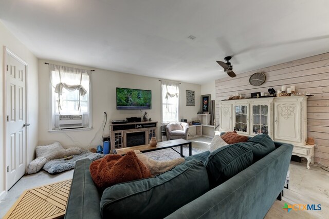 living room with wood walls, cooling unit, ceiling fan, and a fireplace