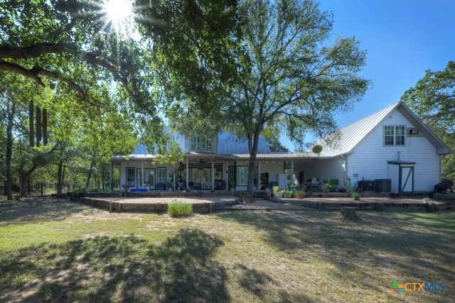 back of house with central AC unit, a lawn, and a patio