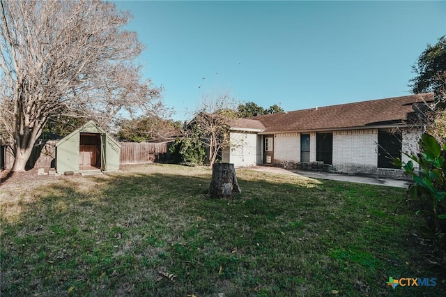 view of yard with a storage shed, a patio area, fence, a garage, and an outdoor structure