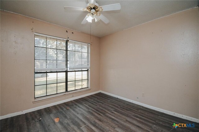 spare room featuring ceiling fan, dark wood finished floors, and baseboards