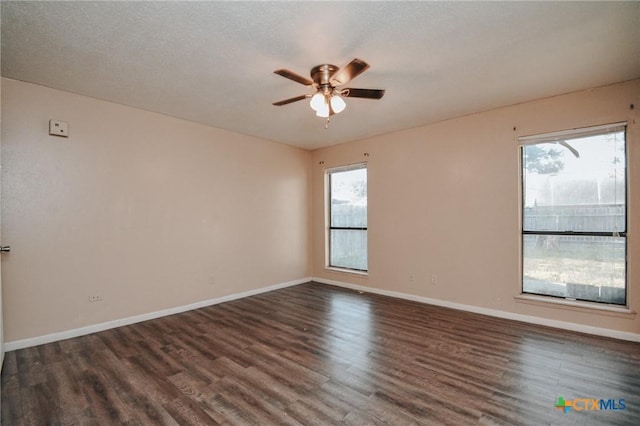 unfurnished room with dark wood-type flooring, ceiling fan, a textured ceiling, and baseboards