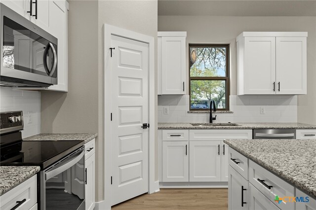 kitchen featuring light stone counters, sink, white cabinets, and appliances with stainless steel finishes