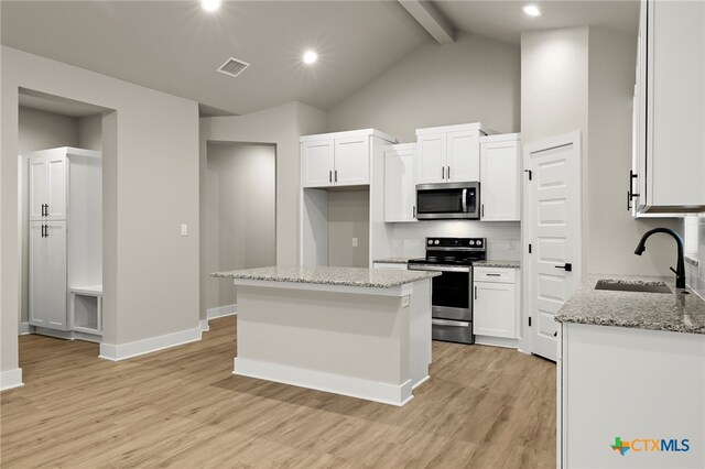 kitchen with sink, light hardwood / wood-style floors, appliances with stainless steel finishes, a kitchen island, and light stone counters