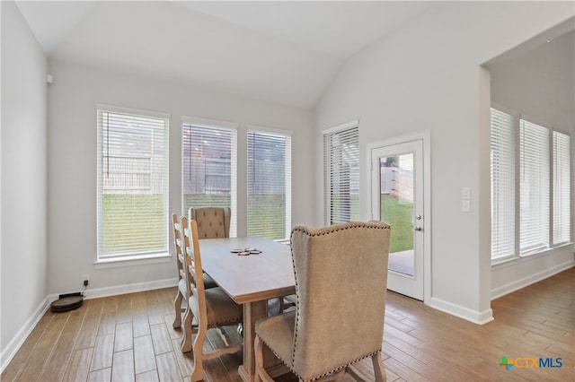 dining area with a wealth of natural light, wood-type flooring, and vaulted ceiling