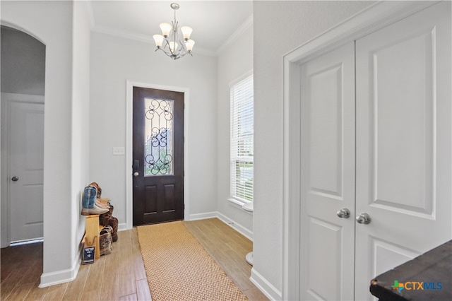 entryway featuring an inviting chandelier, hardwood / wood-style floors, and ornamental molding