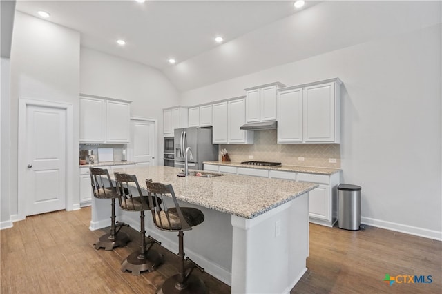 kitchen featuring a center island with sink, sink, appliances with stainless steel finishes, a breakfast bar area, and light wood-type flooring