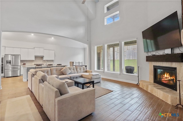 living room featuring a high ceiling, light wood-type flooring, and a tile fireplace