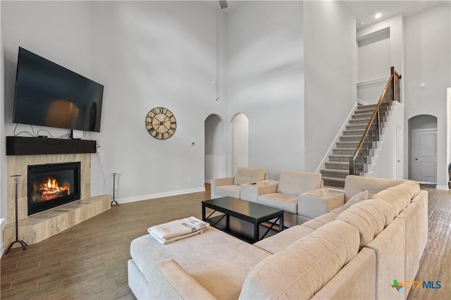 living room with a towering ceiling, dark wood-type flooring, and a tile fireplace