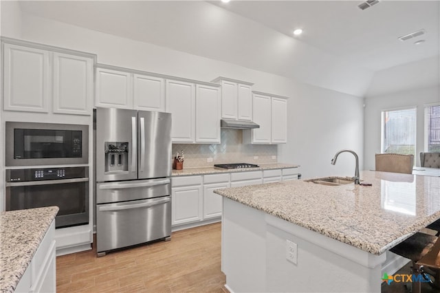 kitchen featuring black appliances, tasteful backsplash, light wood-type flooring, sink, and vaulted ceiling