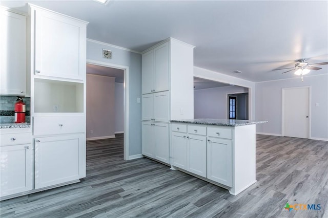 kitchen with white cabinetry, light wood-type flooring, ceiling fan, light stone countertops, and backsplash