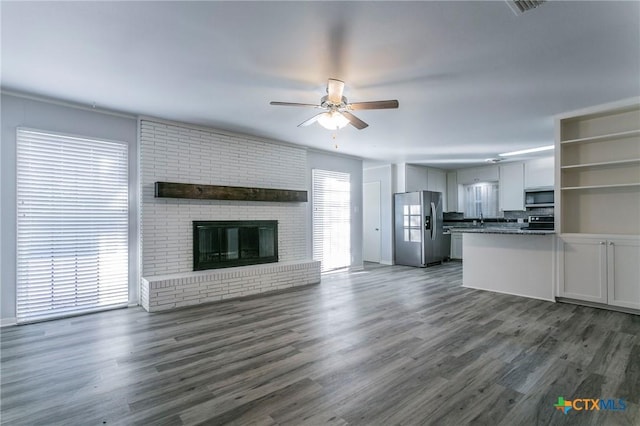 unfurnished living room featuring ceiling fan, dark hardwood / wood-style floors, and a fireplace