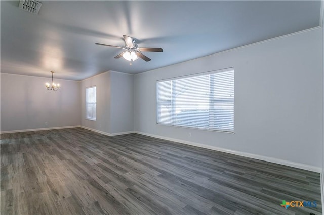 empty room featuring dark hardwood / wood-style floors, ceiling fan with notable chandelier, and a wealth of natural light