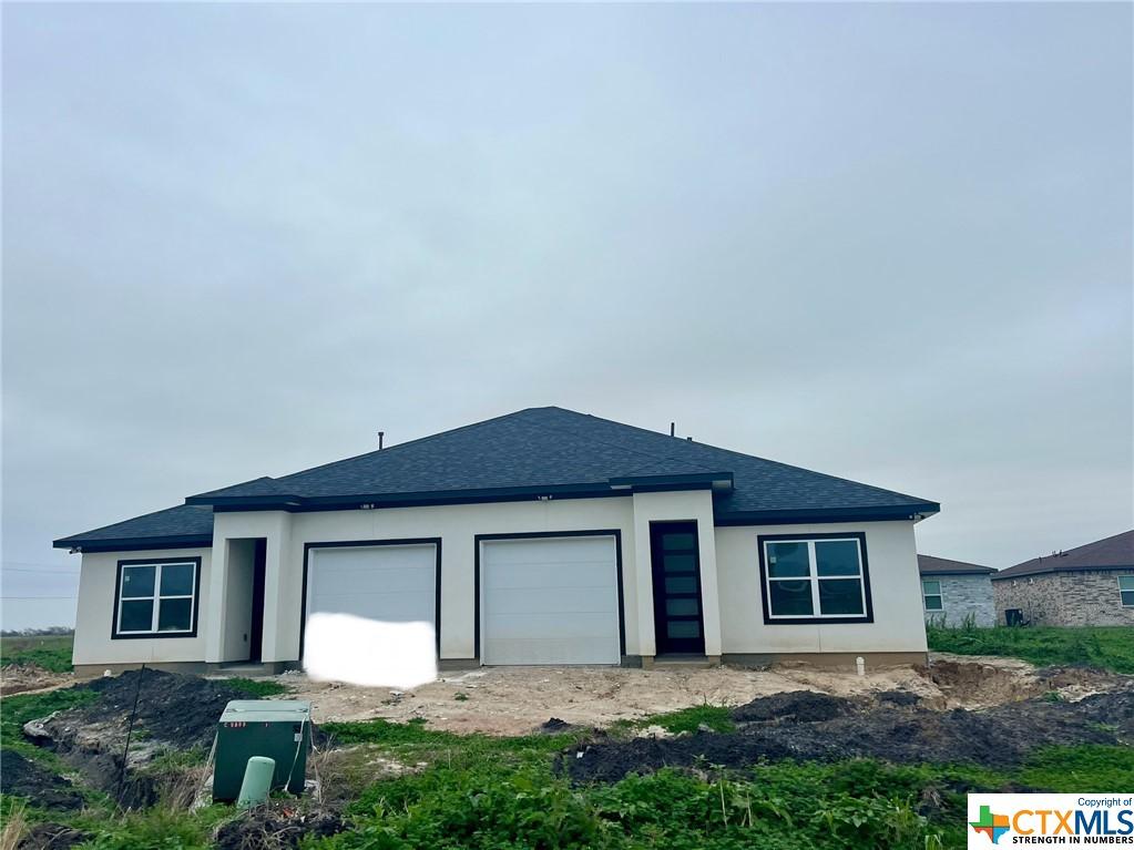 121 W Aimable St, Port Lavaca, TX 77979 - prairie-style home with an attached garage, a shingled roof, and stucco siding