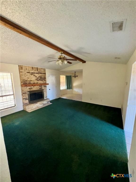 unfurnished living room featuring carpet, vaulted ceiling with beams, ceiling fan, a fireplace, and a textured ceiling