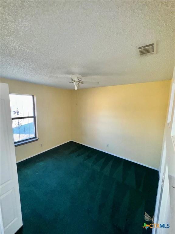 carpeted spare room featuring ceiling fan and a textured ceiling