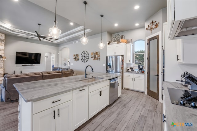 kitchen featuring white cabinets, stainless steel appliances, a center island with sink, and sink