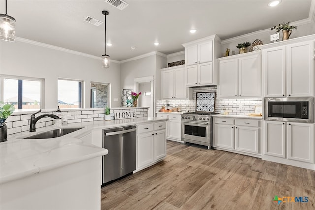 kitchen with stainless steel appliances, hanging light fixtures, white cabinets, and sink