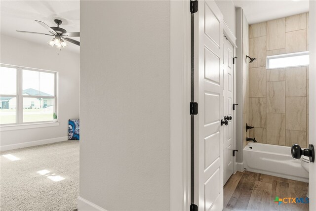 bathroom featuring tiled shower / bath combo, hardwood / wood-style flooring, and ceiling fan