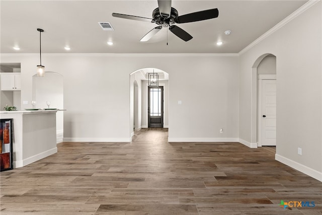 unfurnished living room with hardwood / wood-style floors, ceiling fan, and ornamental molding