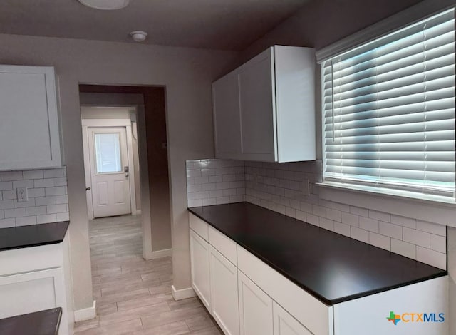 kitchen with white cabinetry, light wood-type flooring, and backsplash