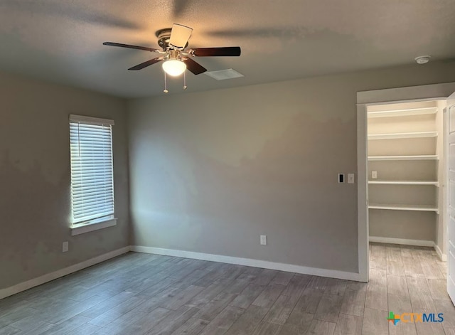 empty room featuring a textured ceiling, ceiling fan, and light wood-type flooring