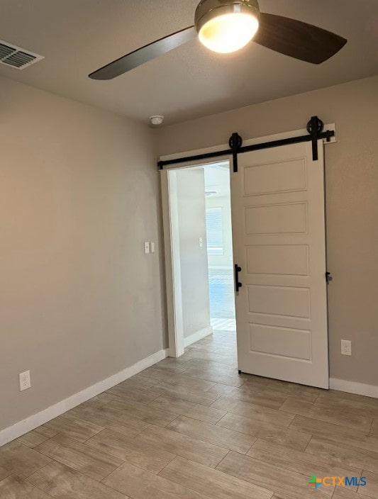 empty room featuring a barn door and ceiling fan