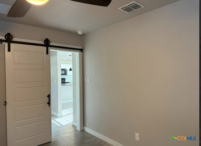 hallway featuring a barn door and light hardwood / wood-style flooring