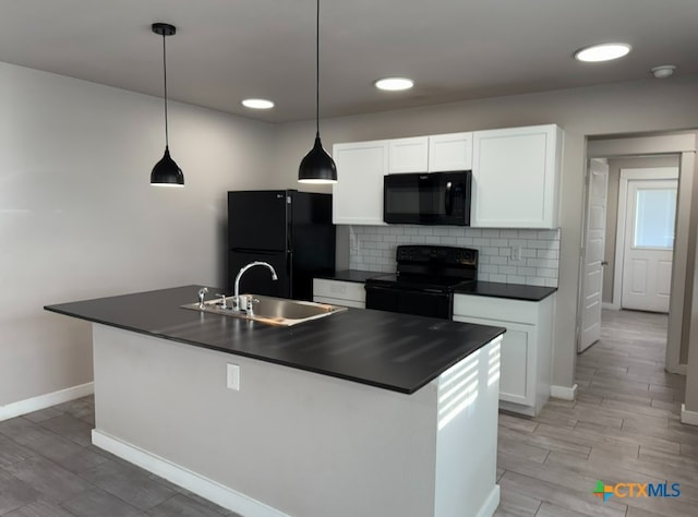 kitchen featuring decorative light fixtures, a kitchen island with sink, sink, and black appliances