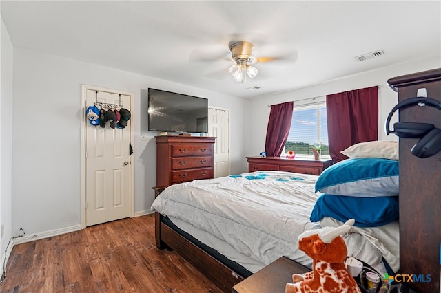 bedroom with dark hardwood / wood-style flooring, ceiling fan, and a closet