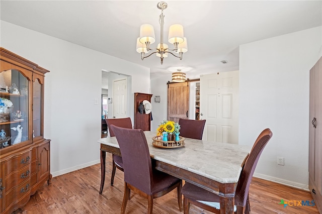 dining space featuring hardwood / wood-style floors, a barn door, and a chandelier