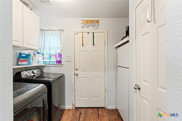 laundry room featuring cabinets, washing machine and dryer, a textured ceiling, and hardwood / wood-style flooring