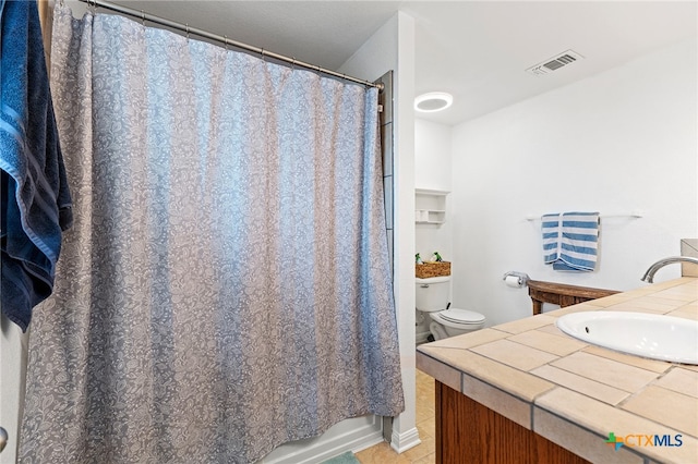 bathroom featuring toilet, vanity, and tile patterned flooring