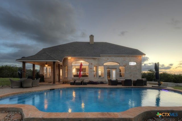 pool at dusk with a patio and an outdoor living space