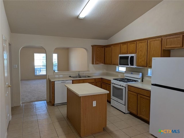 kitchen with a center island, white appliances, sink, light tile patterned floors, and a textured ceiling