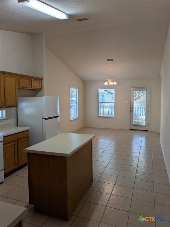 kitchen with a center island, white refrigerator, light tile patterned floors, decorative light fixtures, and a chandelier