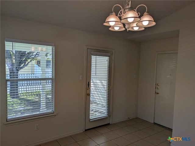 doorway featuring plenty of natural light, light tile patterned flooring, and an inviting chandelier